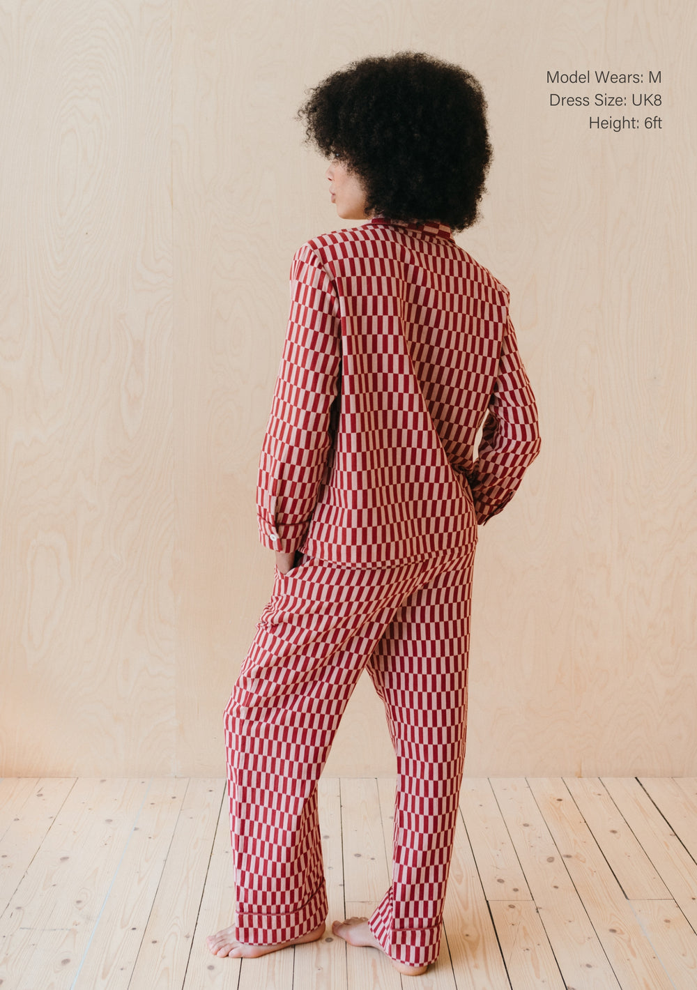 Back view of TBCo Cotton Pyjamas in Rose Checkerboard pattern, showing oversized fit and full-length style on wooden floor