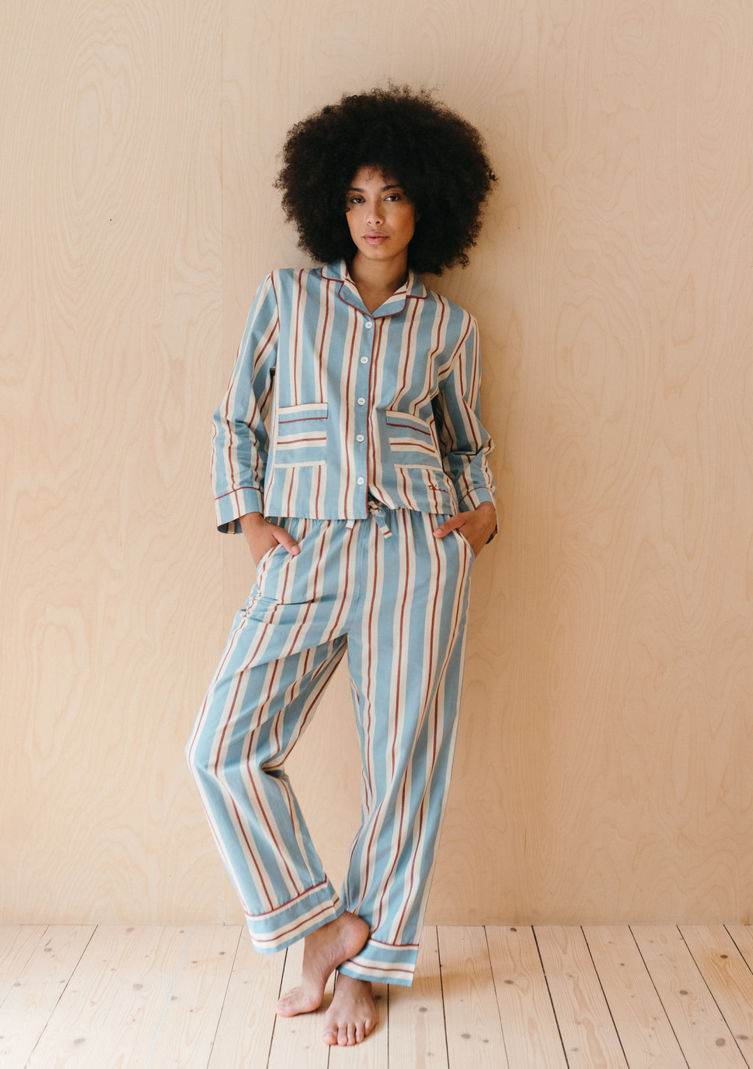 TBCo Cotton Pyjamas in blue, red and cream stripes shown with collared top and matching trousers against wooden backdrop