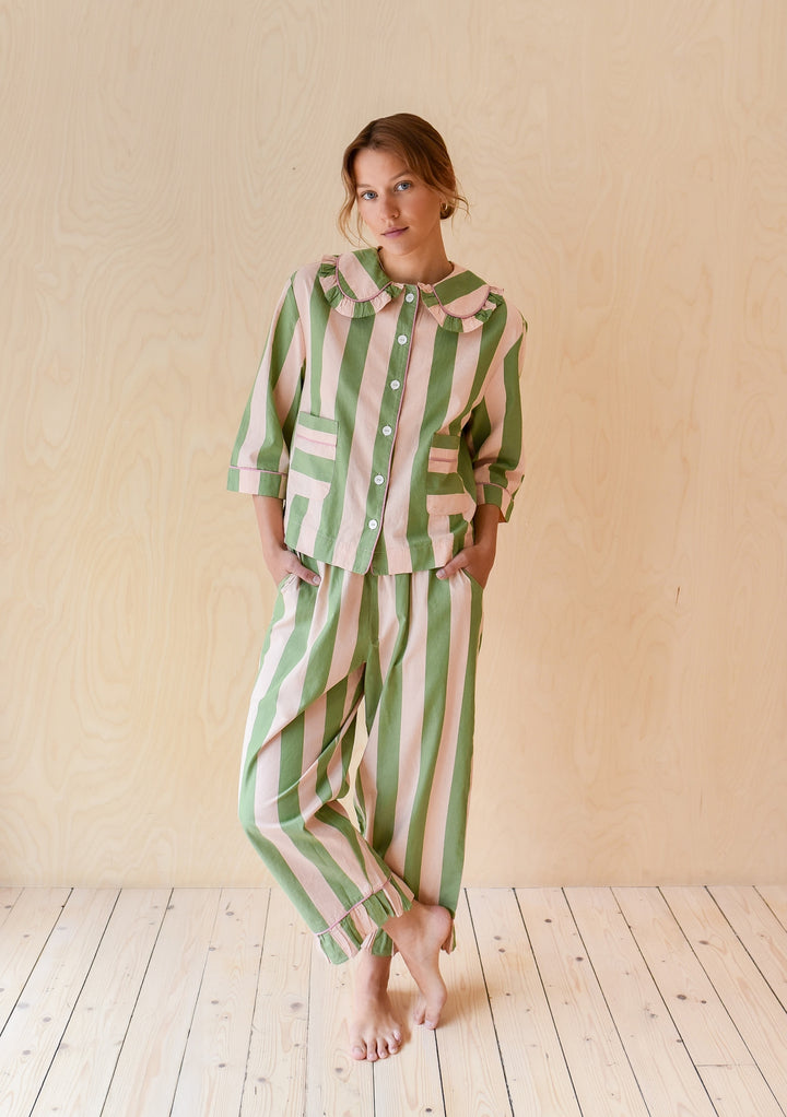 Model wearing TBCo Cropped Cotton Pyjamas in Green Stripe with buttoned top and relaxed striped trousers on wooden floor