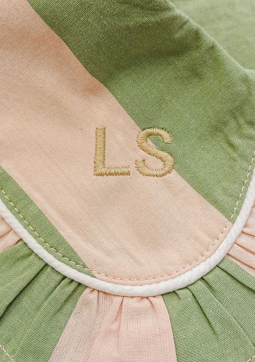 Close-up detail of monogrammed LS initials on TBCo Cotton Pyjamas in Green Stripe, showing embroidery on pink and green fabric