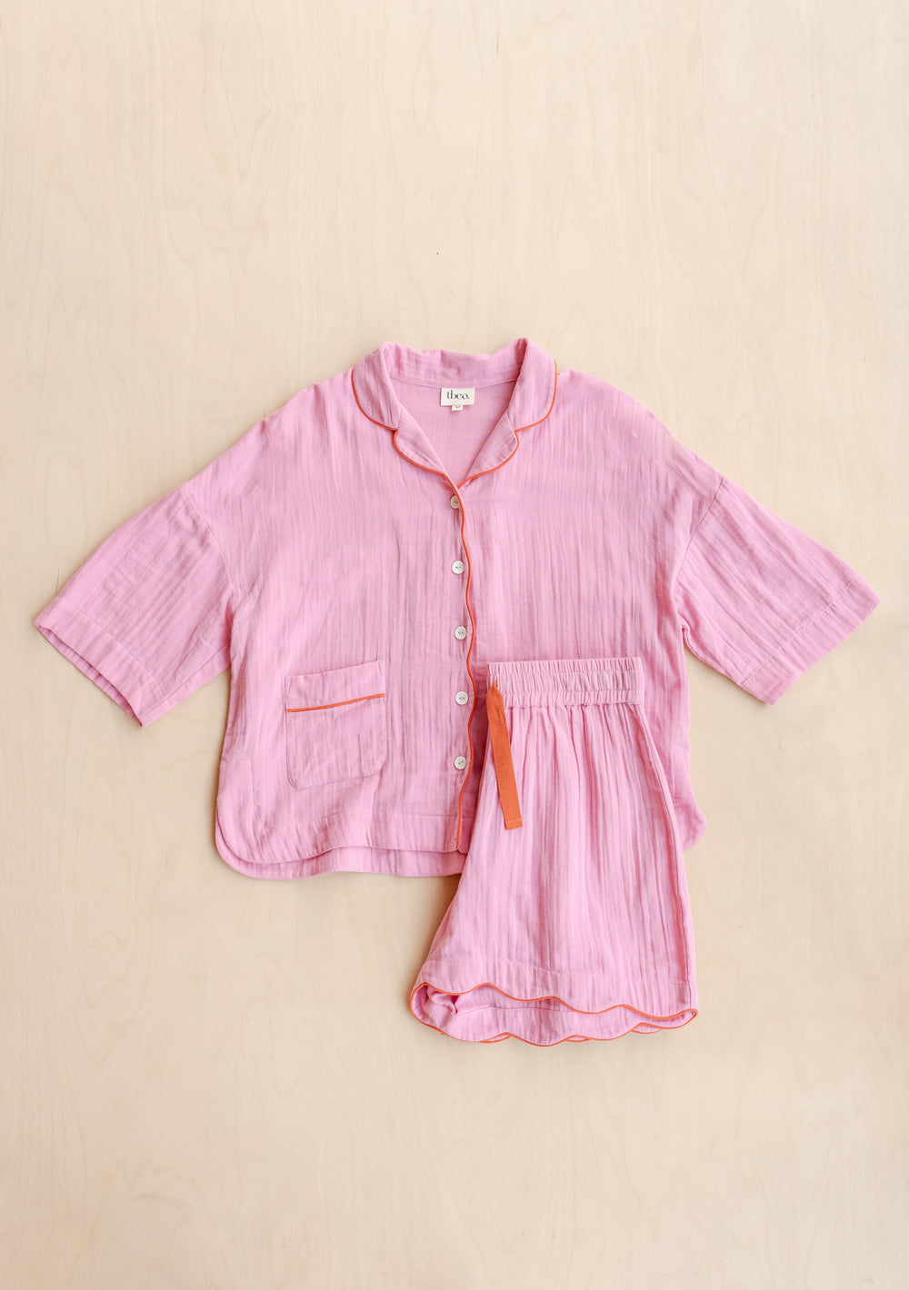 TBCo Cotton Pyjamas in Pink Scallop featuring orange piping, embroidered details and matching shorts on beige background