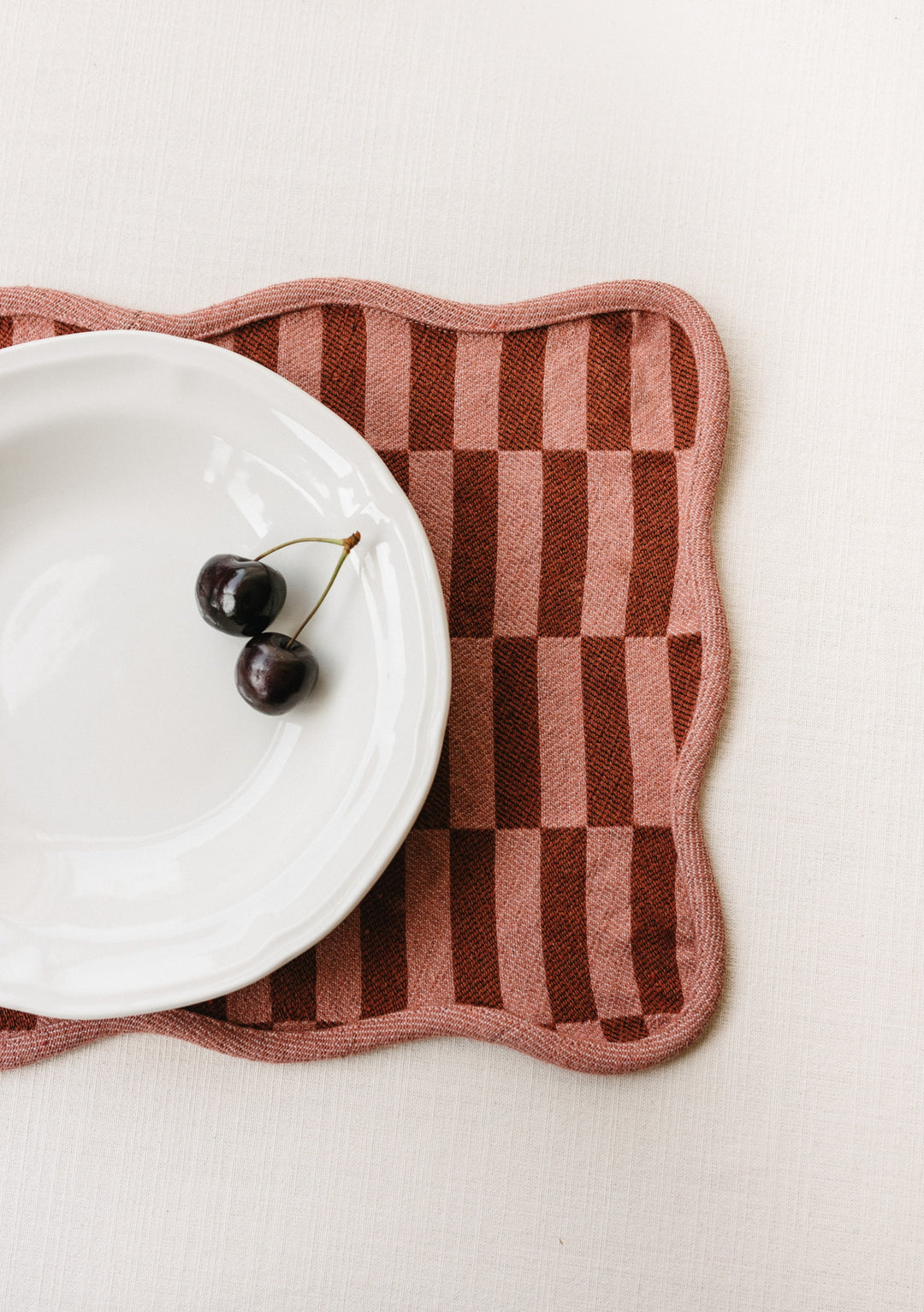 TBCo Cotton Placement Set of 2 featuring rose checkerboard pattern with scalloped edges and contrast piping, styled with cherries