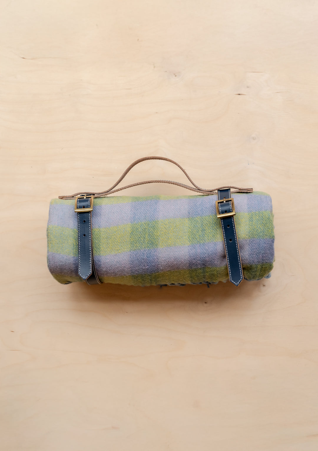 TBCo Recycled Wool Picnic Blanket in green gingham pattern, rolled with leather carrying straps on cream background