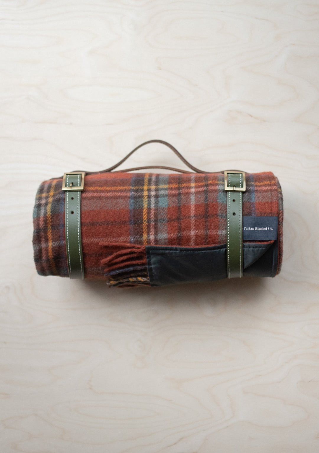 TBCo Recycled Wool Picnic Blanket in Stewart Royal Antique Tartan rolled with leather carry straps and waterproof backing