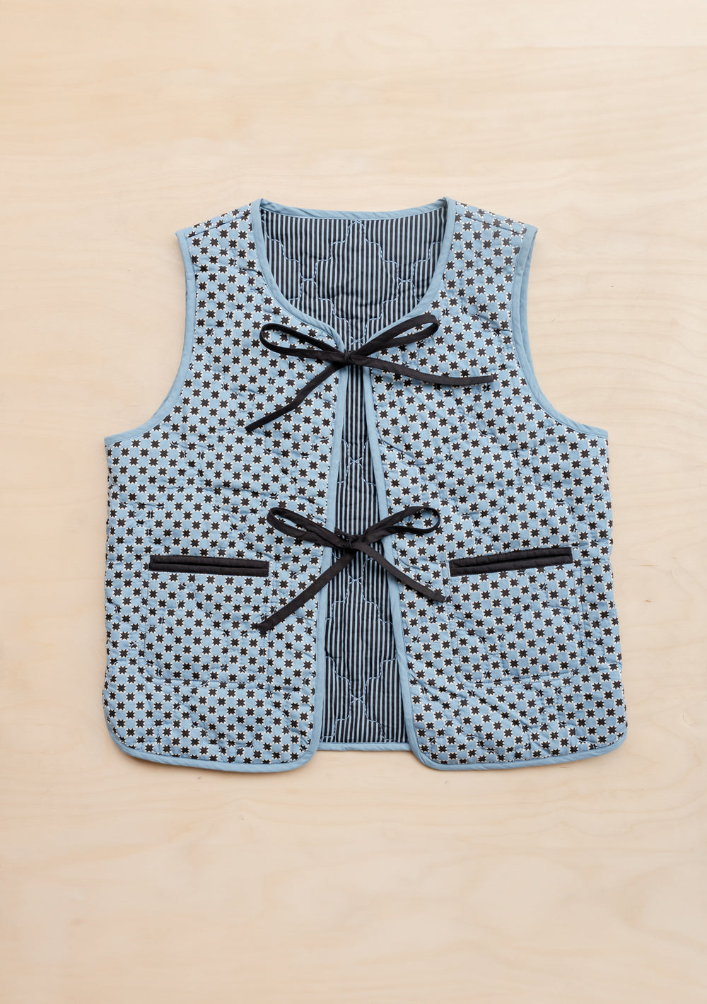 TBCo reversible quilted cotton vest in blue celestial stripe pattern with black bow fastenings and convenient pockets