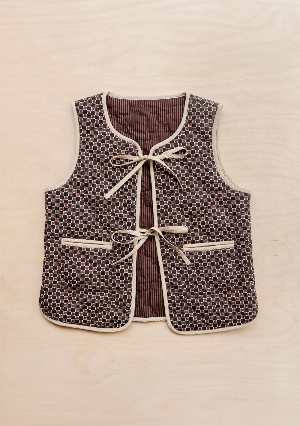 TBCo Quilted Cotton Vest in Reversible Brown Celestial Stripe with bow fastenings and pockets, displayed flat against cream background