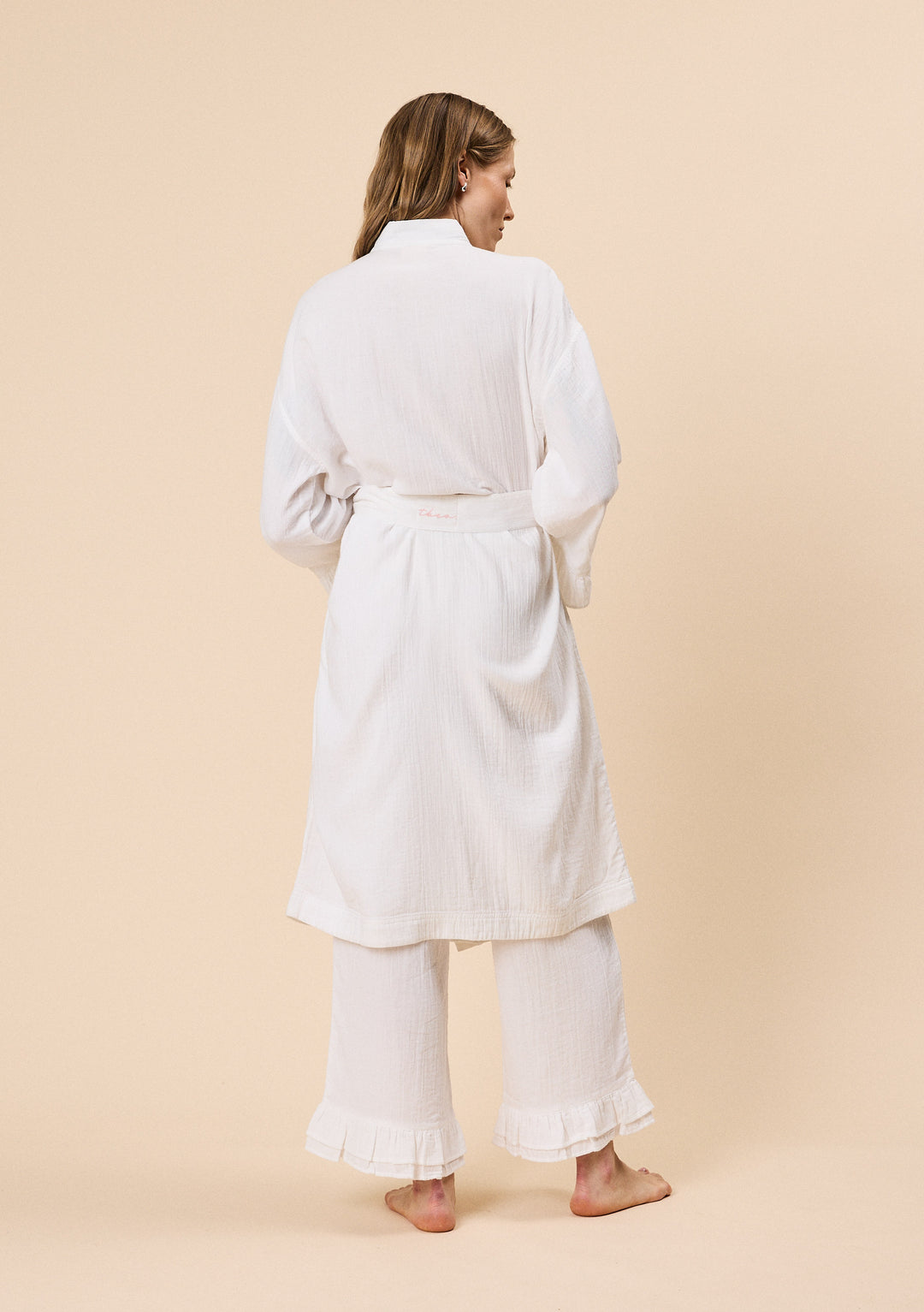 Back view of woman wearing TBCo Cotton Robe in White Ruffle with natural & recycled fibres, Certified B-Corp, women-founded, designed to make an impact
