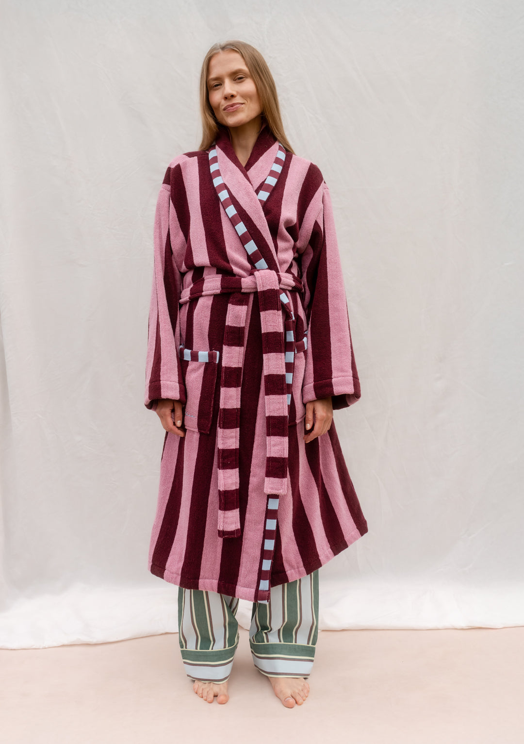 Woman wearing TBCo Cotton Bath Robe in Burgundy Stripe with pockets and sash, lightweight and quick-drying cotton design.