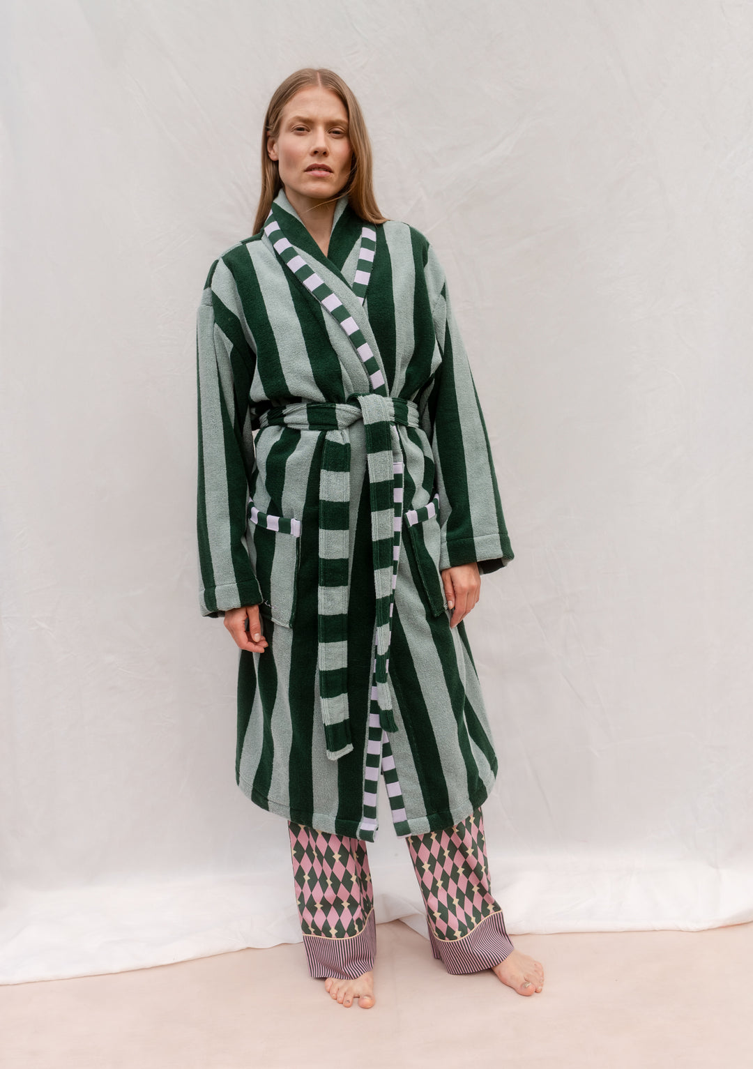 Woman wearing TBCo Cotton Bath Robe in Green Stripe with sash and pockets, standing against plain background.