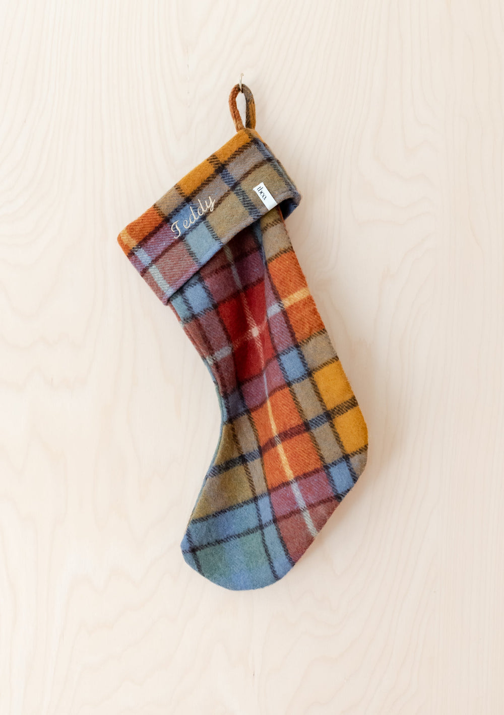 Recycled Wool Christmas Stocking in Buchanan Antique Tartan by TBCo with personalised embroidery hanging on wood background