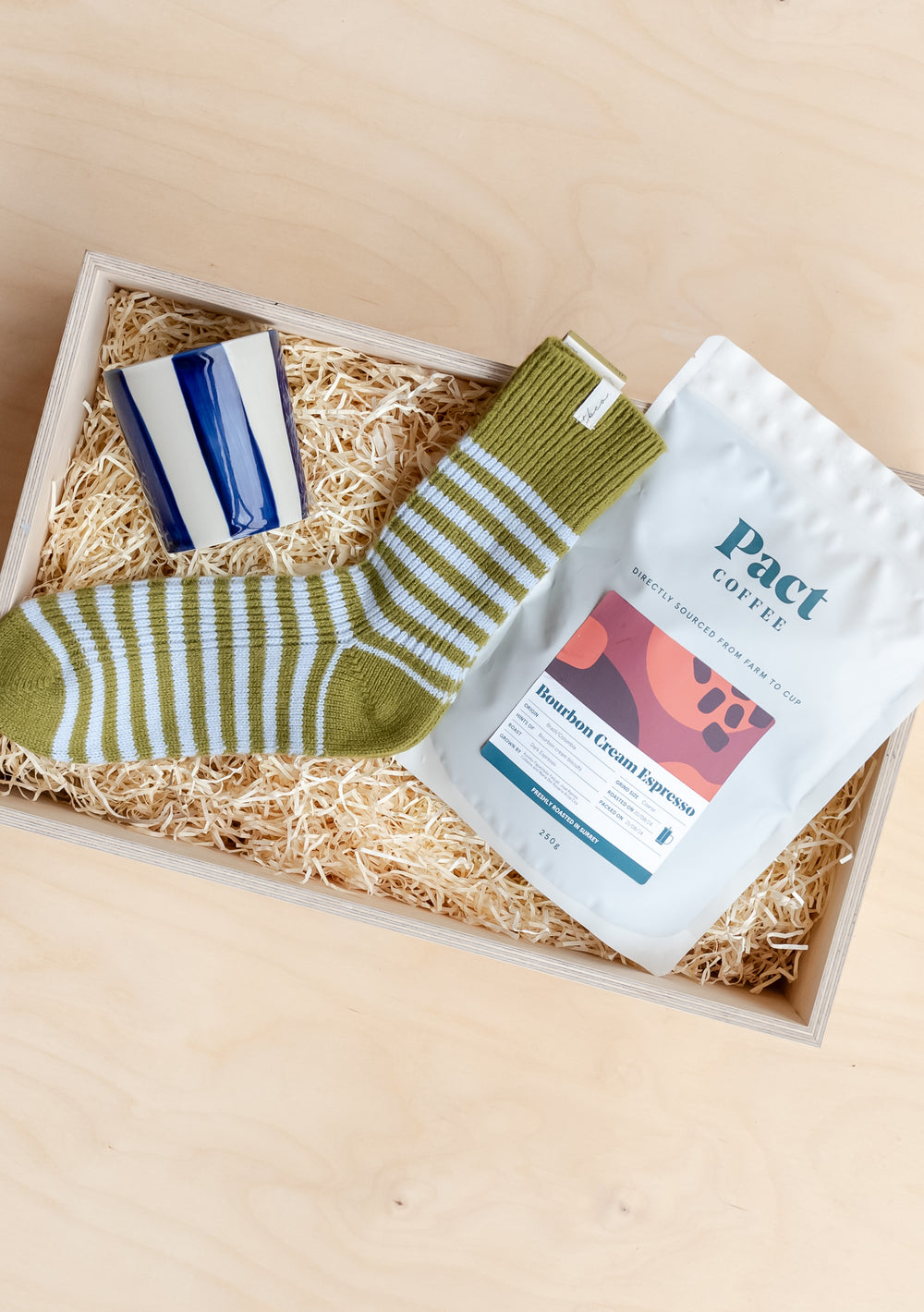 Ready-Made Coffee Lovers Gift Box by TBCo includes olive striped socks, navy mug, and Pact Bourbon Cream Espresso coffee.
