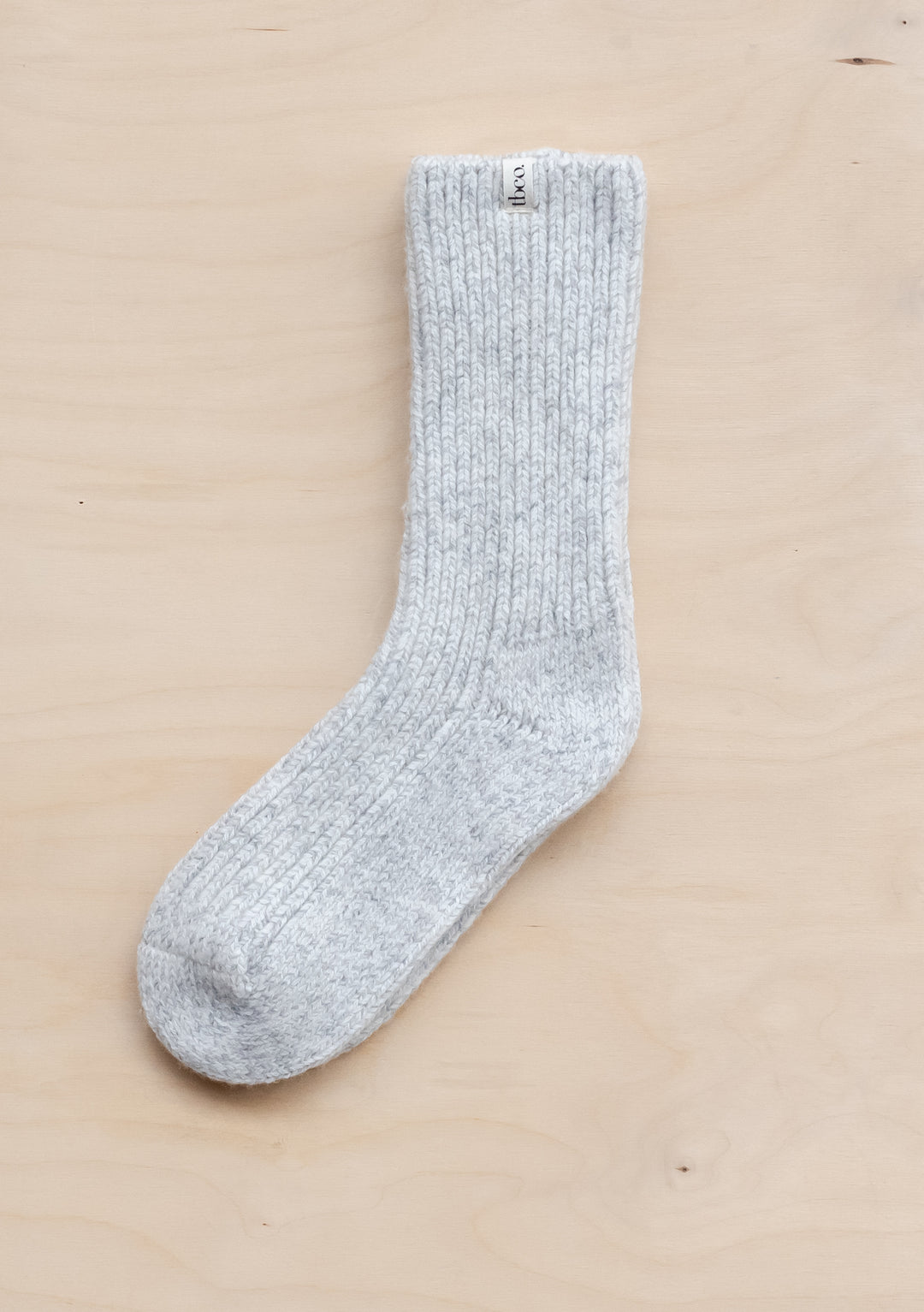 TBCo Cashmere & Merino Socks in Grey Fleck displayed flat on beige surface, showing ribbed texture and flecked wool pattern