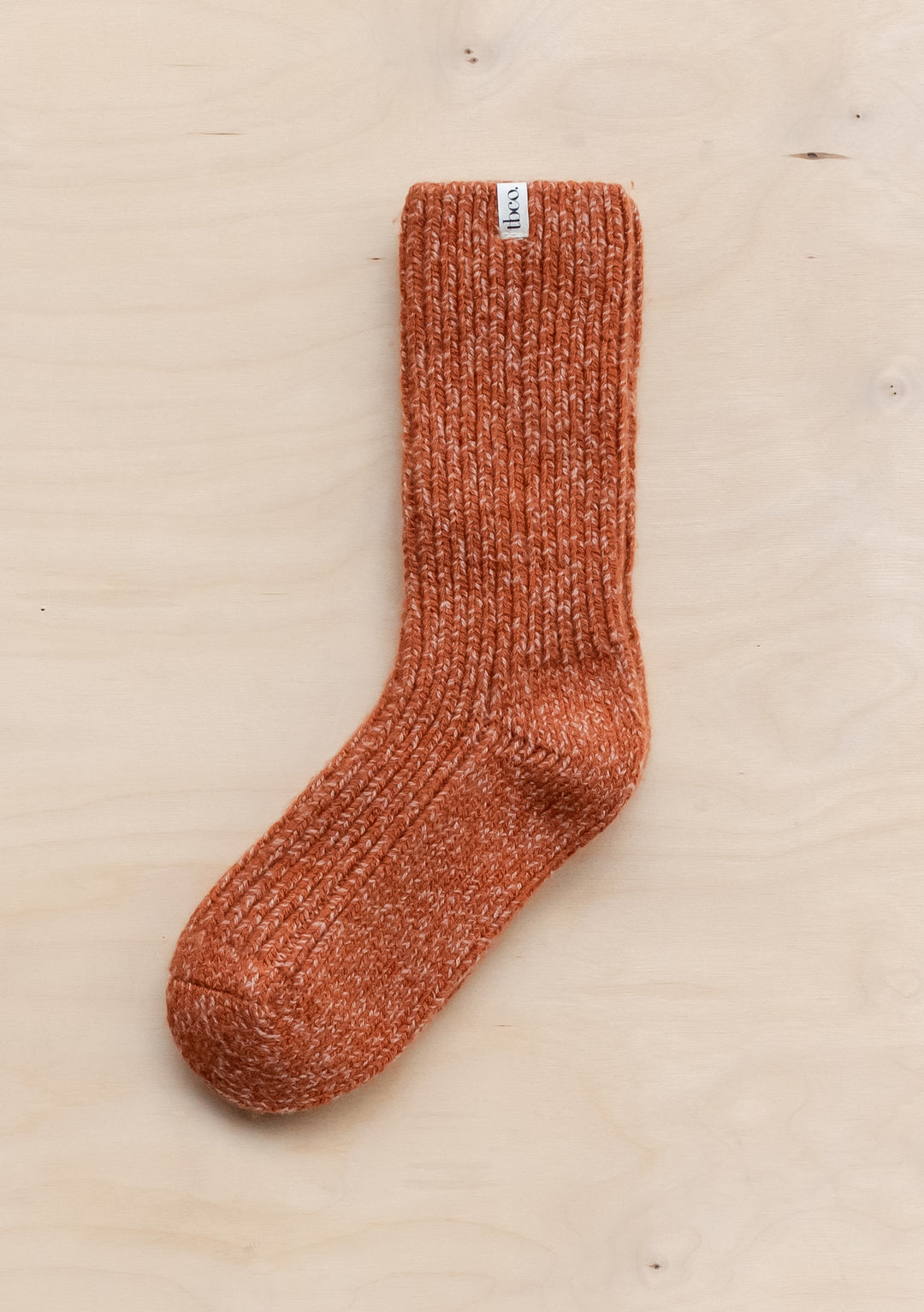 TBCo Cashmere & Merino Socks in Rust Fleck, featuring ribbed texture and speckled wool blend pattern on wooden surface