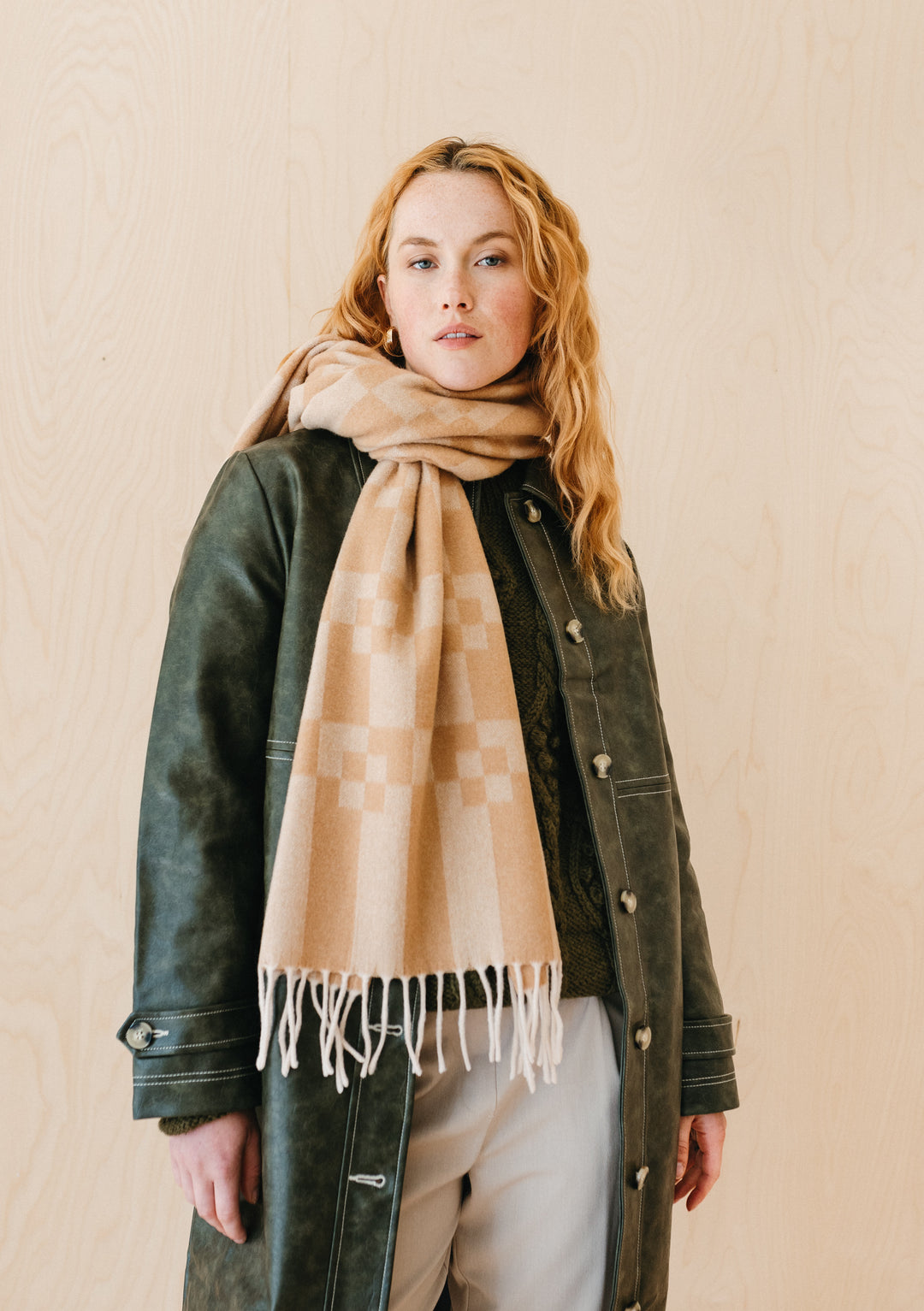 Model wearing TBCo Cashmere & Merino Oversized Scarf in Camel Geometric Block, styled with green coat, showing geometric pattern and fringe