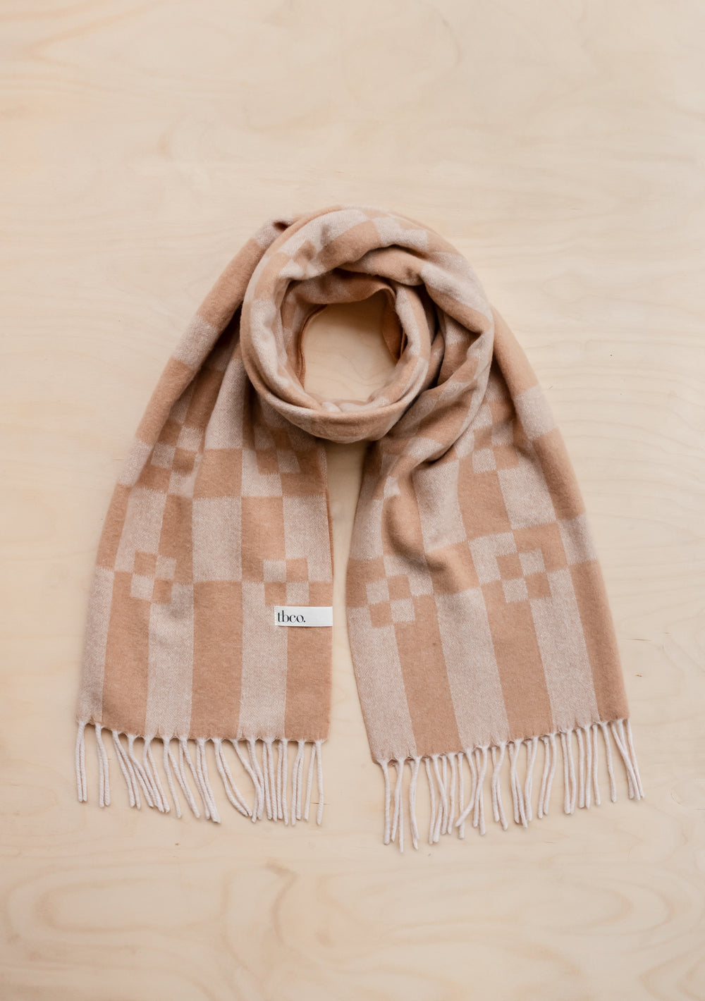 TBCo Cashmere & Merino Oversized Scarf in camel with geometric block pattern, fringed edges, laid flat on beige surface