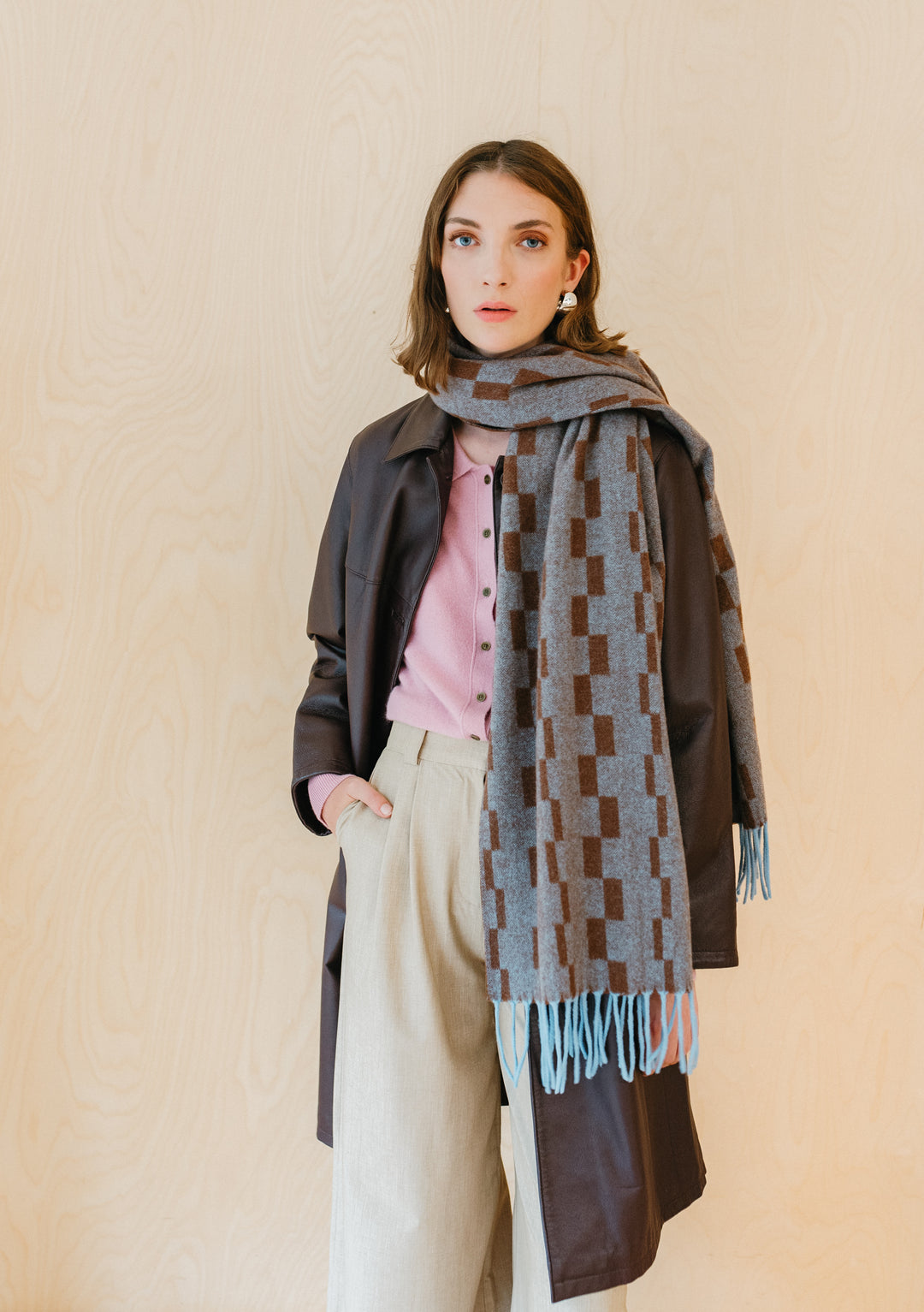 TBCo Lambswool Oversized Scarf in Blue Checker, styled with winter coat and pink cardigan, showcasing fringed checkerboard pattern