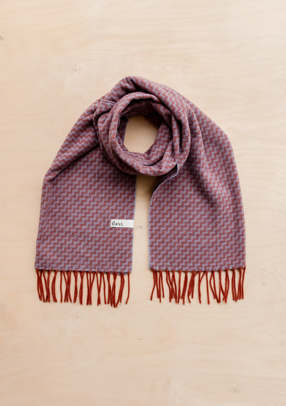 TBCo lambswool oversized scarf in lilac chevron pattern with rust fringe, laid flat against beige background