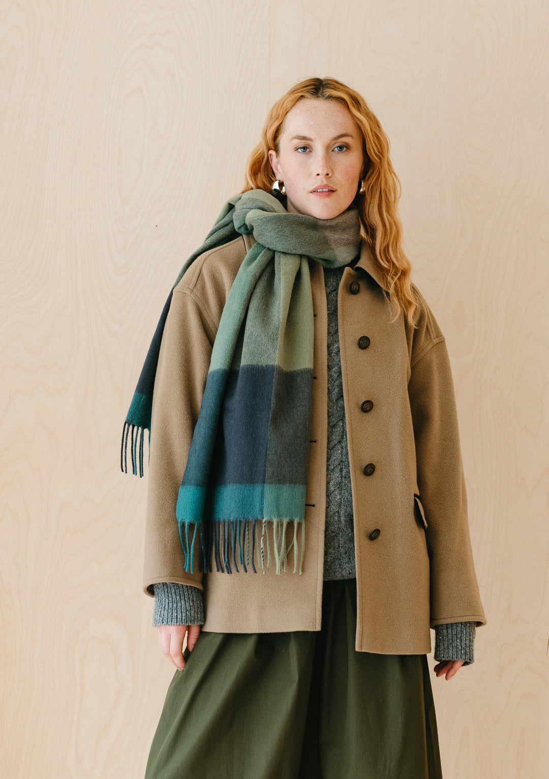 TBCo lambswool oversized scarf in green edge check pattern draped stylishly over beige coat and green skirt ensemble