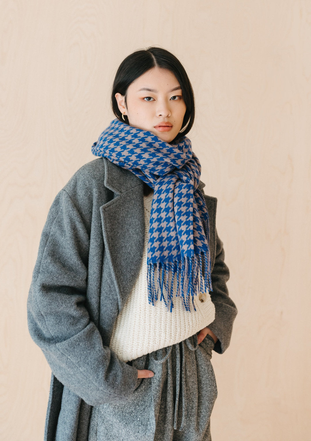 TBCo Lambswool Oversized Scarf in Slate Houndstooth styled on model with grey coat and white jumper against neutral backdrop