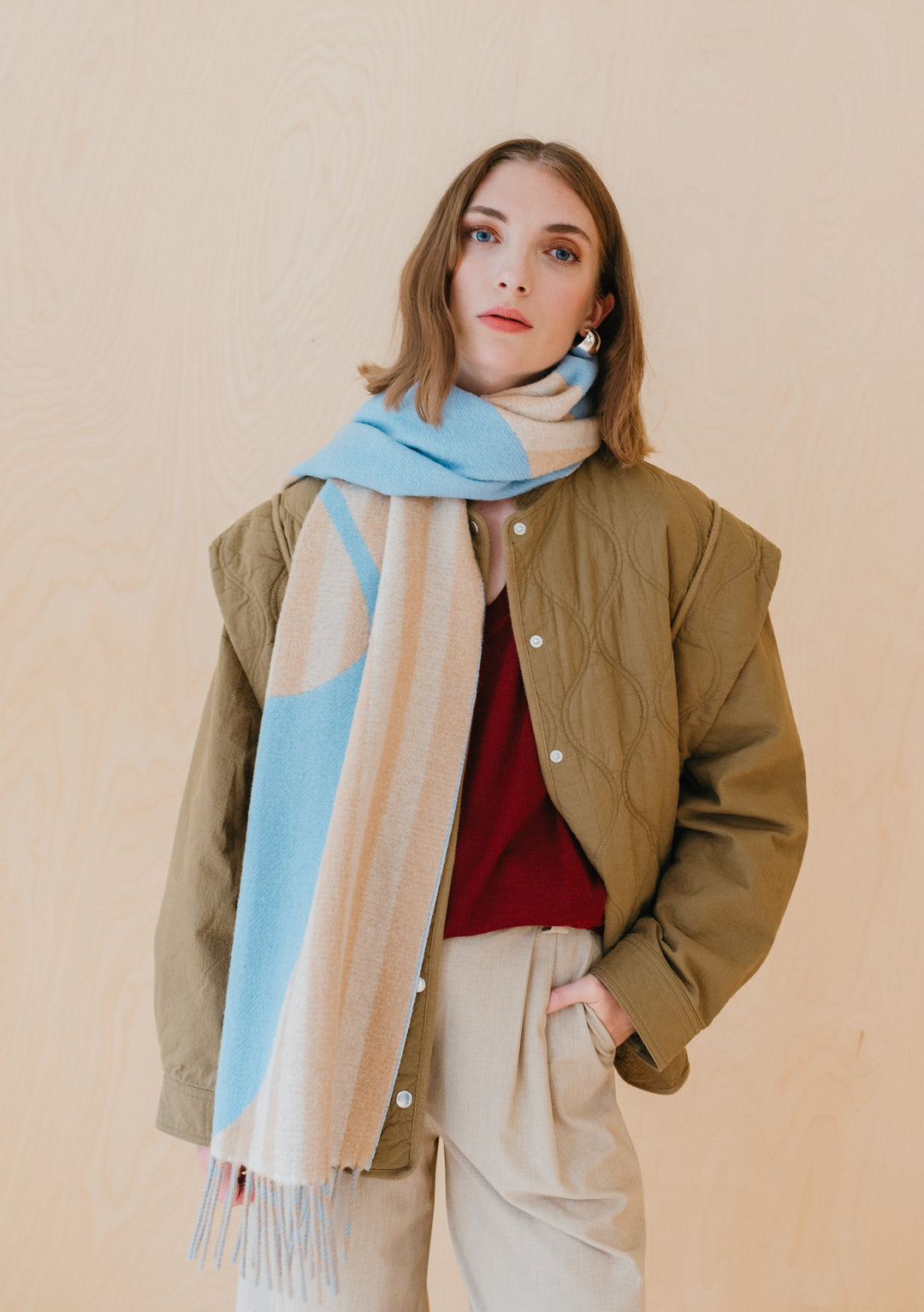 Stylish person wearing TBCo Flora Stripe Jacquard Lambswool Oversized Scarf in blue and camel with quilted jacket and trousers