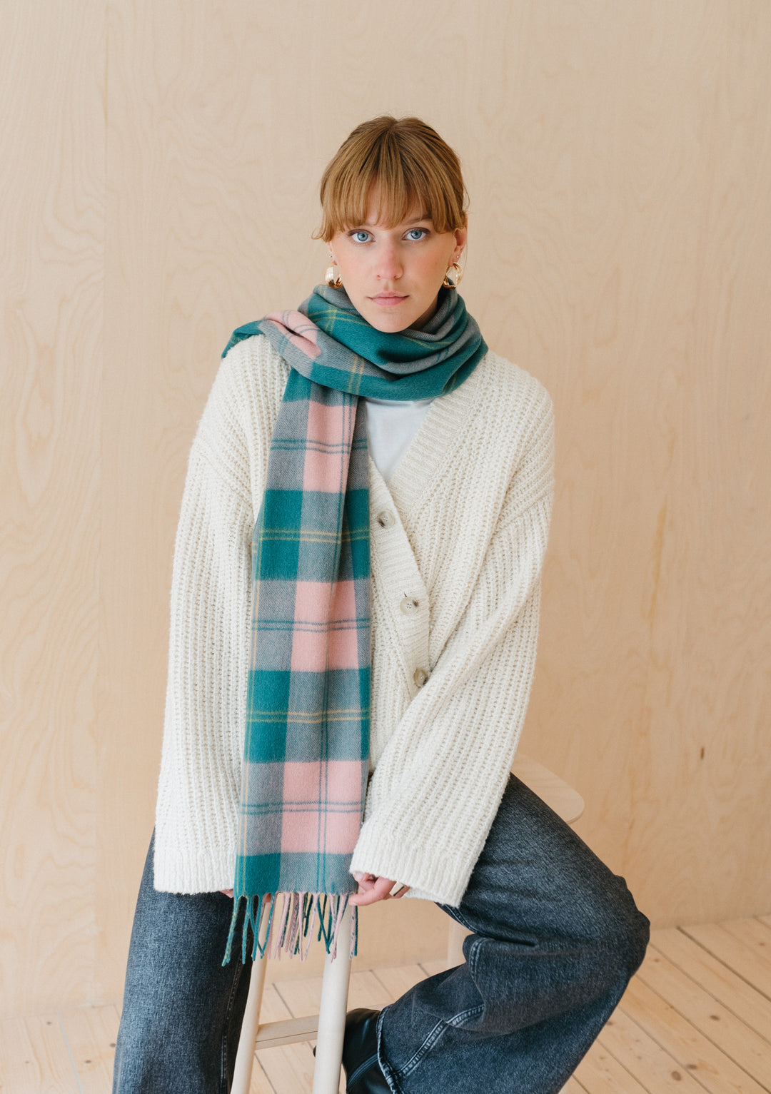 Pink and green varsity check TBCo lambswool scarf styled with white knit sweater and denim against neutral backdrop