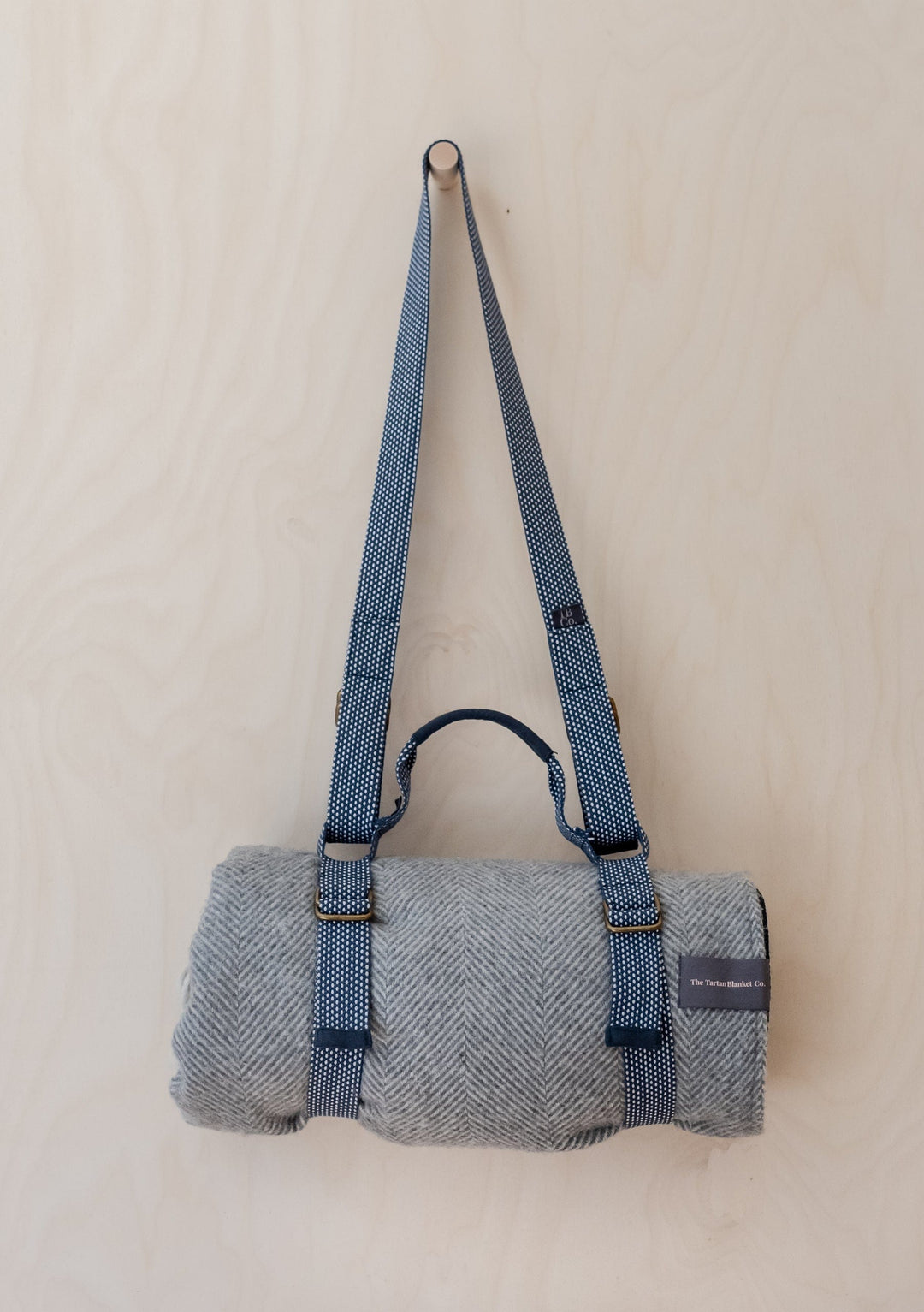 TBCo Recycled Picnic Carrier with grey herringbone blanket rolled and secured by adjustable polka dot shoulder straps