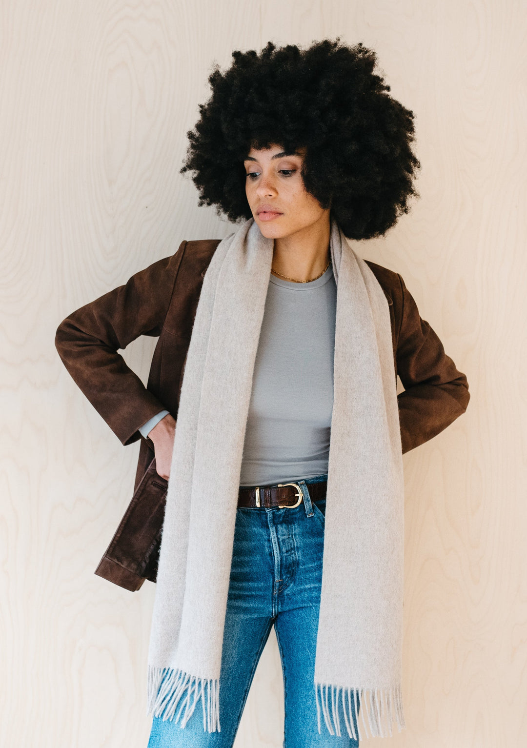 TBCo oatmeal melange lambswool scarf with fringe, styled with brown jacket and jeans, showcasing soft texture and elegant drape