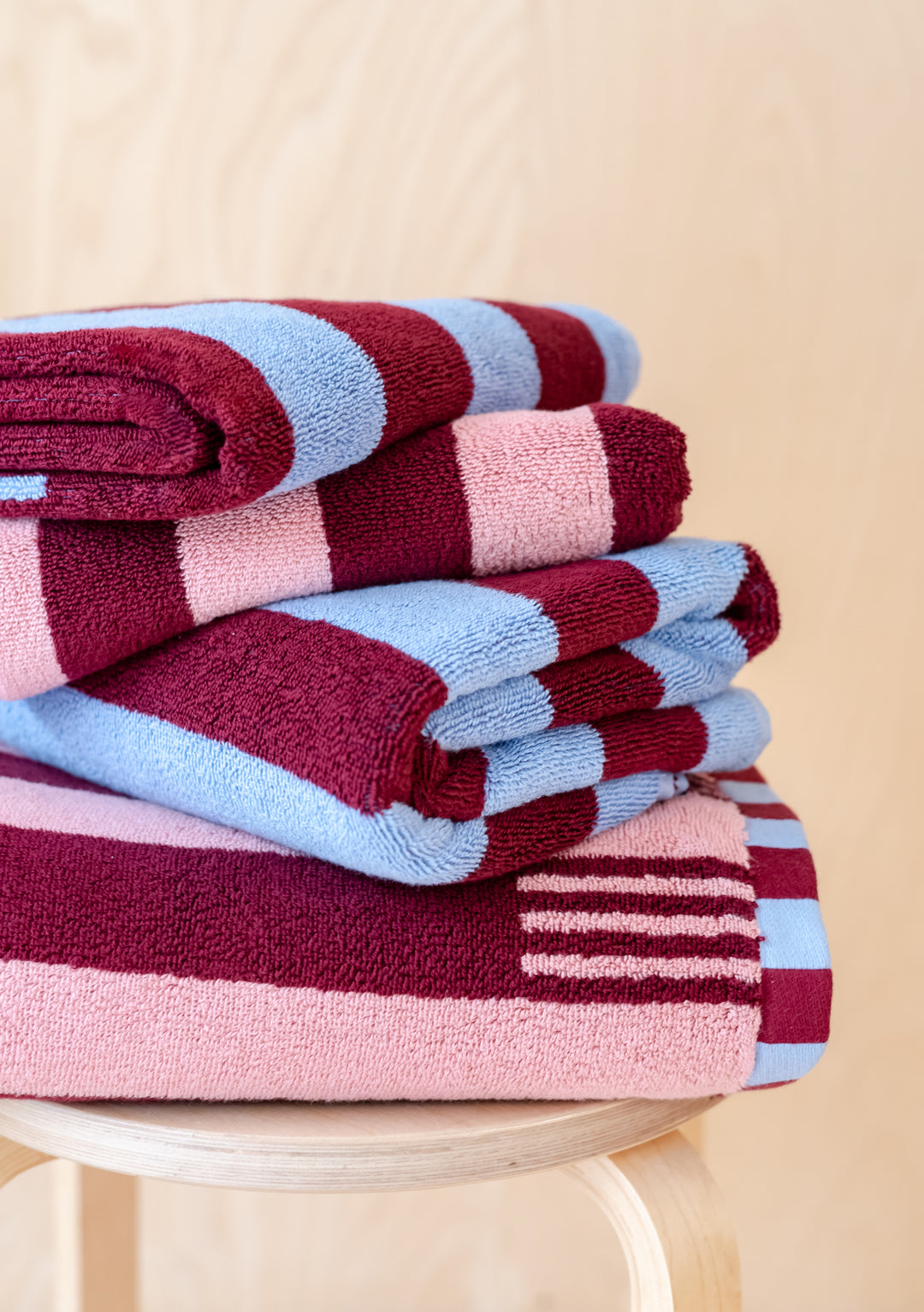 TBCo Mix & Match Towels Set featuring burgundy, pink and blue striped cotton towels stacked neatly on wooden surface