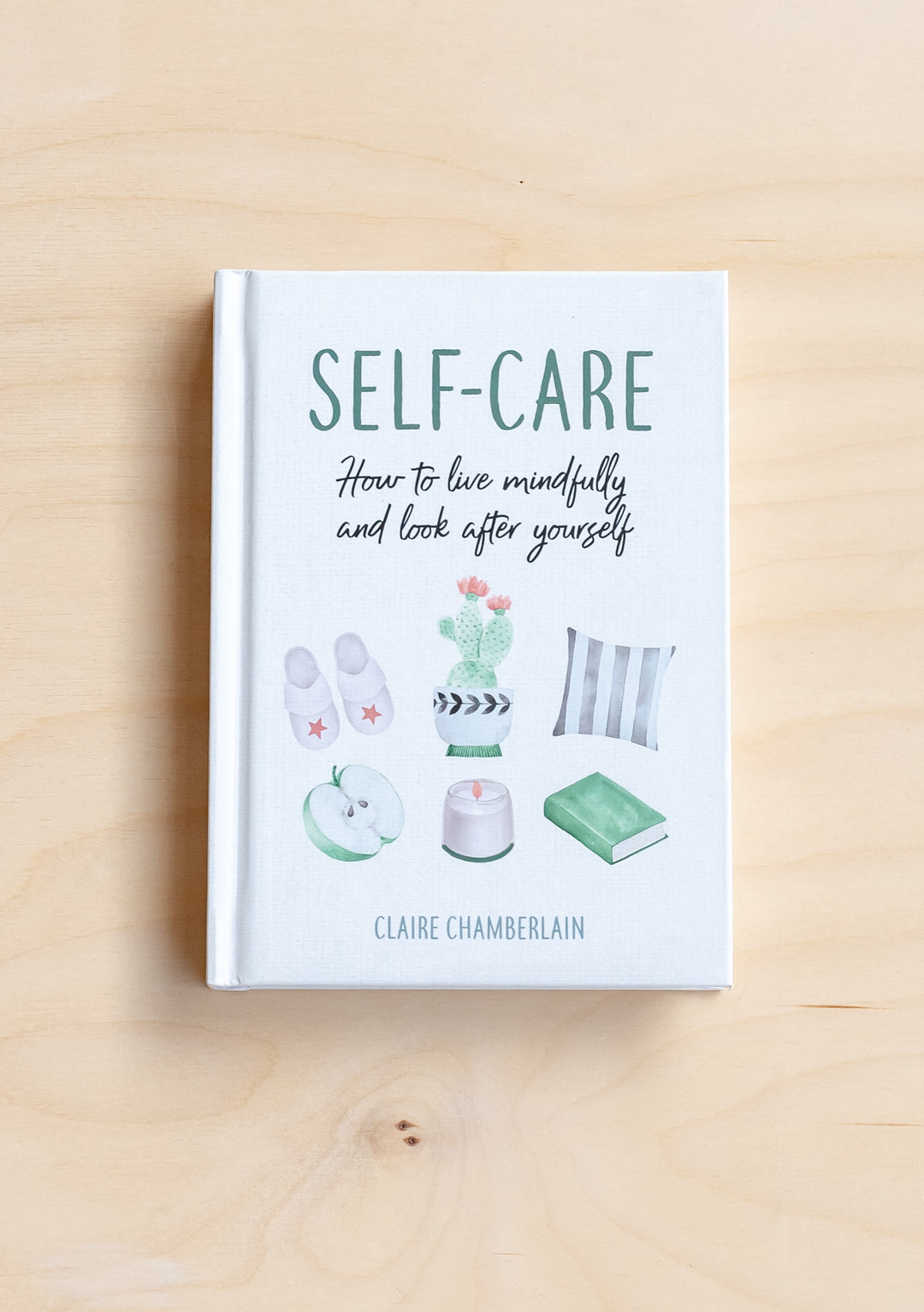 TBCo Self-Care Book on a light wooden surface showing mindful living tips and gentle pastel illustrations.