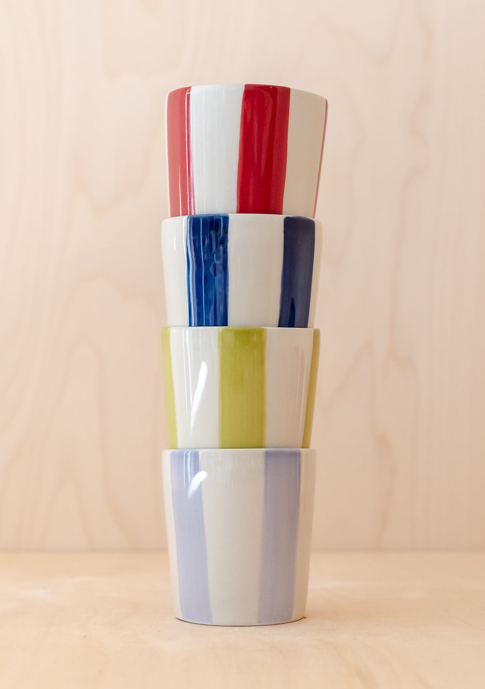 Handcrafted TBCo Green Stripe Mug stacked with other striped ceramic mugs in red, blue and grey against neutral background