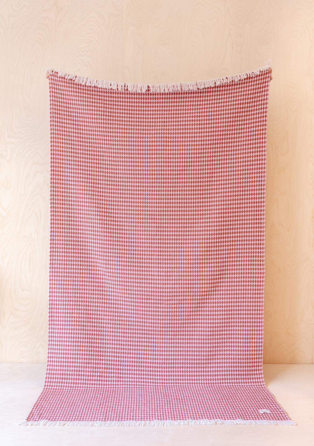 TBCo Cotton Throw in Pink Argyle displayed vertically, showing full-length houndstooth pattern in pink and white against neutral backdrop