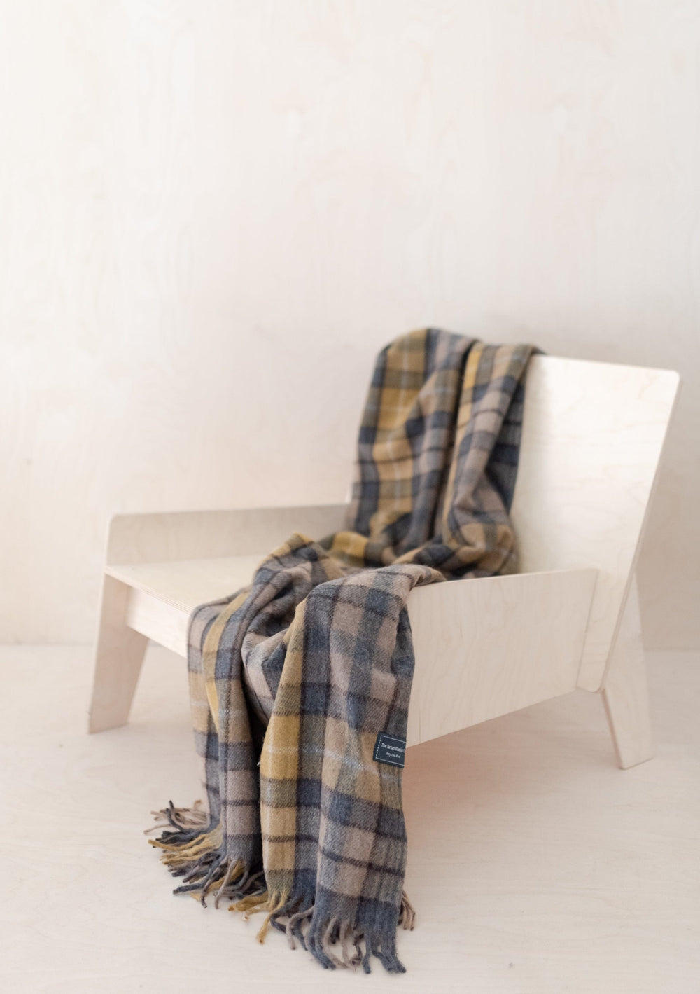 TBCo Ready-Made Scottish Treats Gift Box featuring a tartan wool blanket draped over white chair, showcasing classic plaid pattern