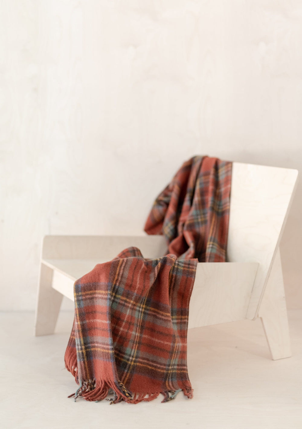 TBCo Ready-Made Scottish Gift Box featuring tartan wool blanket draped over white chair, displaying classic Highland style