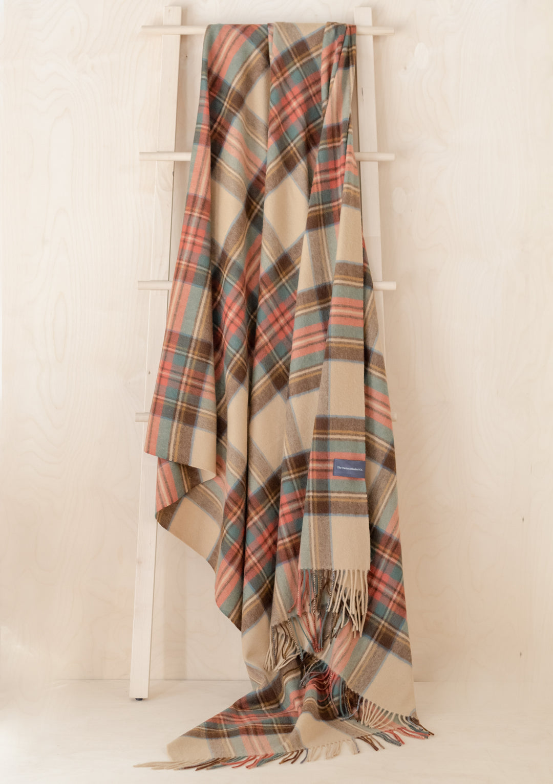 TBCo Stewart Dress Antique Tartan cashmere blanket draped elegantly on white ladder, showcasing traditional plaid pattern and fringe