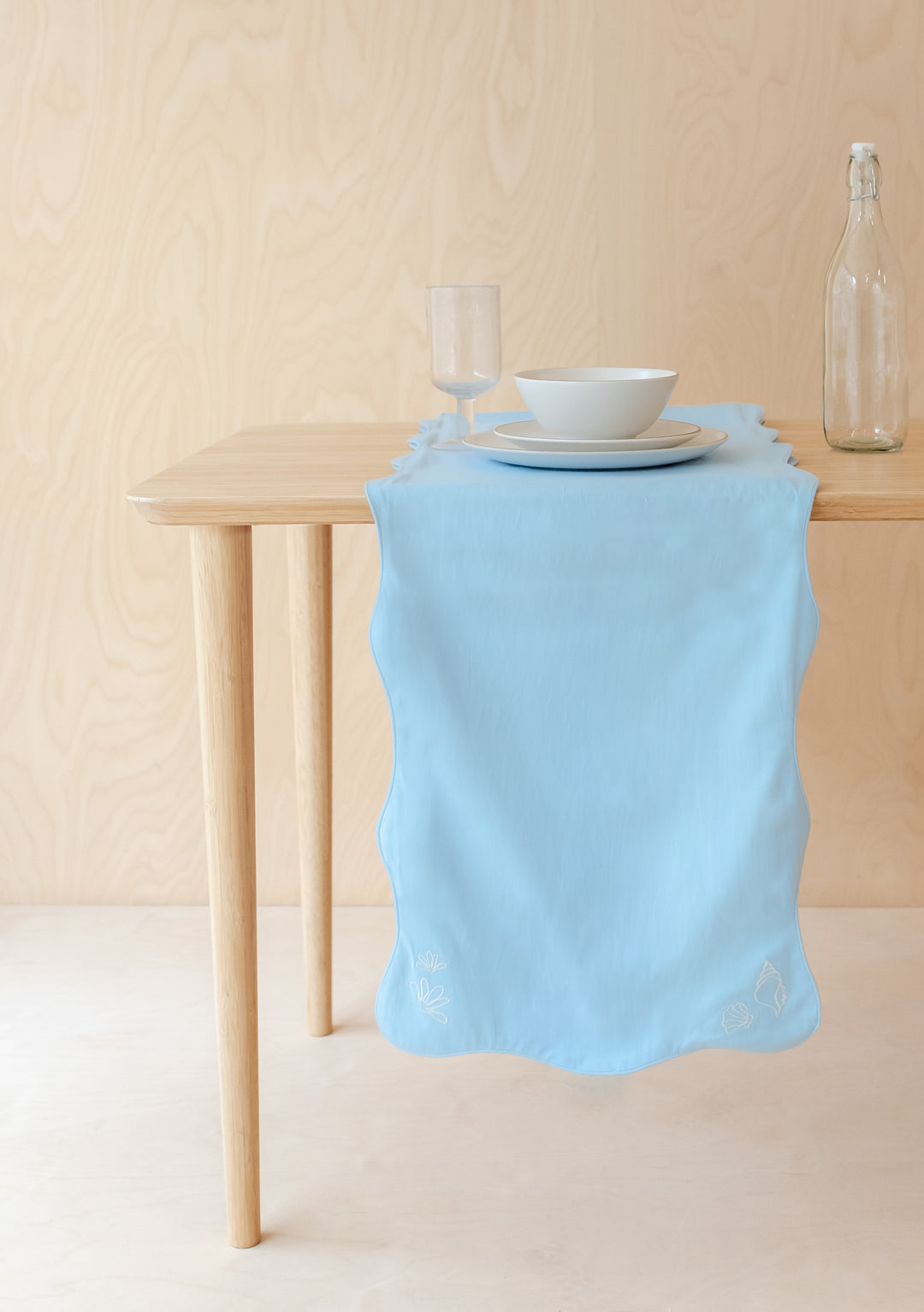 TBCo cotton and linen table runner in light blue with scalloped edges and seashell embroidery on wooden dining table