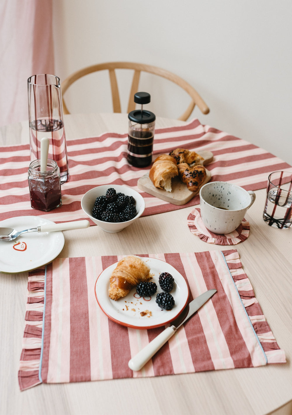 TBCo Cotton Runner in Red Stripe displayed on breakfast table with croissants and blackberries, showcasing frilled edges and striped pattern