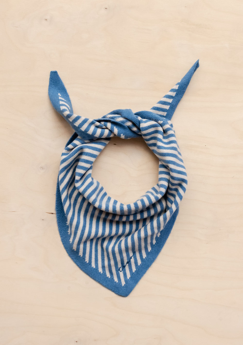 TBCo Merino Triangle Scarf in blue and cream stripes, tied in a classic bandana style on beige background