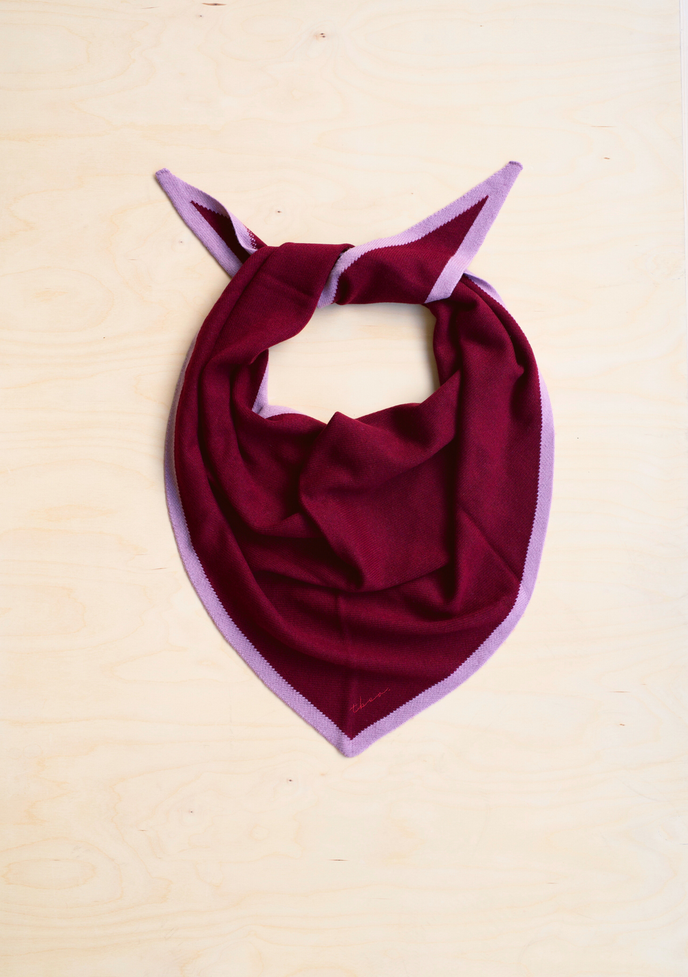 Large Merino Wool Triangle Scarf from TBCo with burgundy and pink accents on a beige background