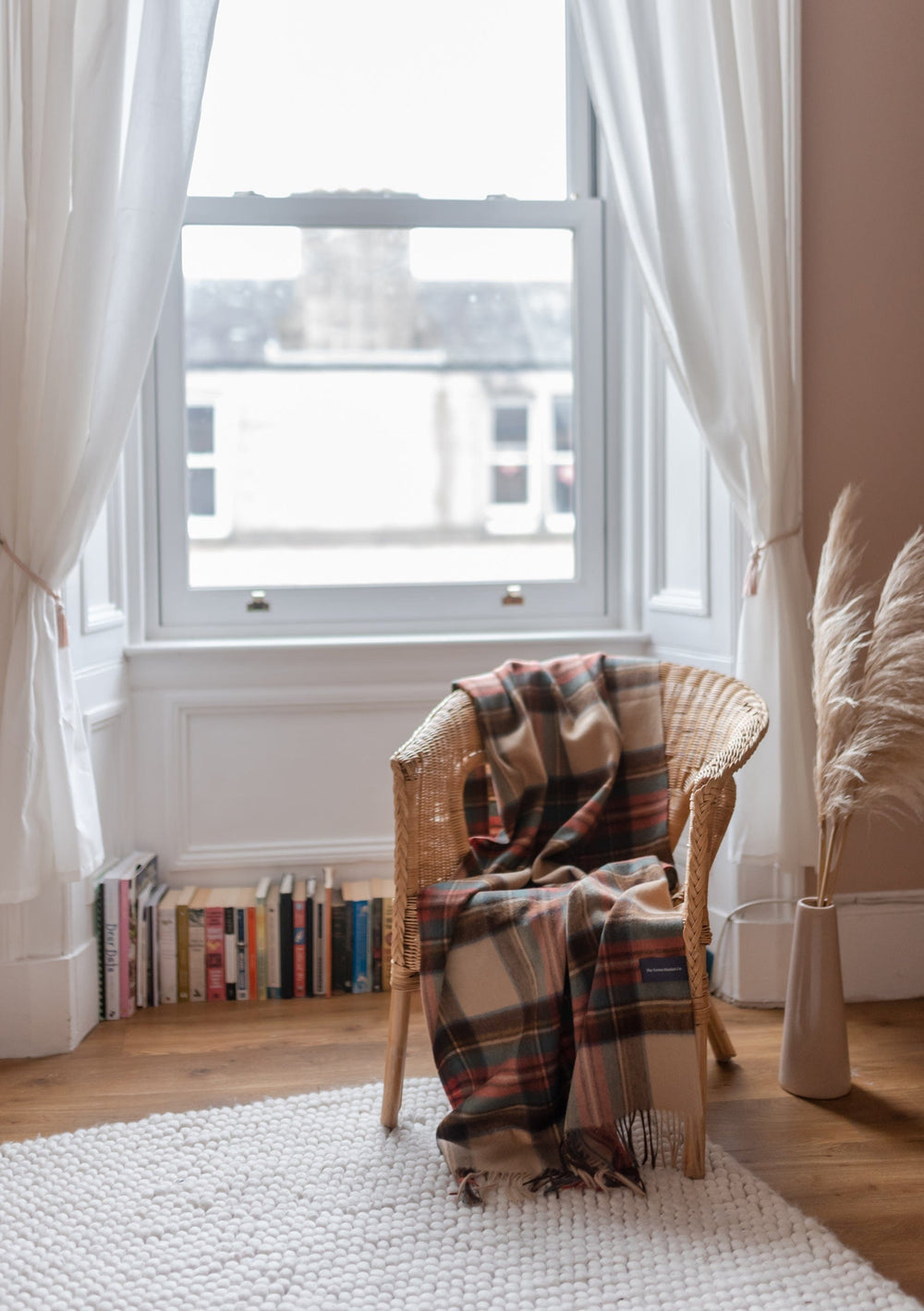 TBCo Lambswool Small Blanket in Stewart Dress Antique Tartan draped over wicker chair by bright window with white curtains