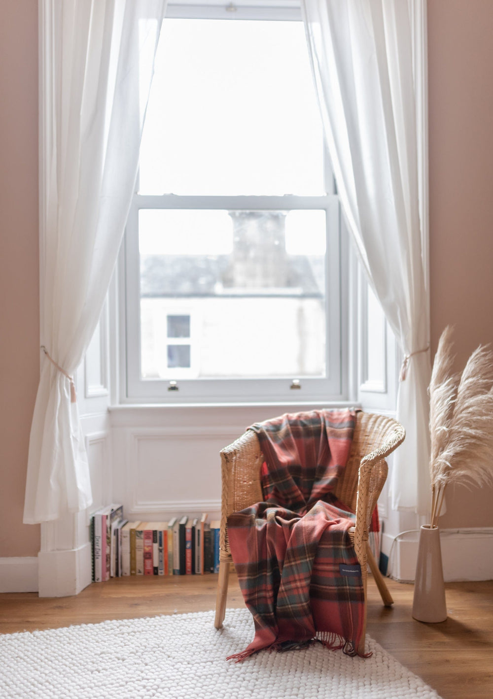 TBCo Stewart Royal Antique Tartan Lambswool Blanket draped over wicker chair by bright window with white curtains